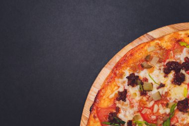 Tahtada kağıt üzerinde pizza. Siyah bir masada pizza, yakın plan. Sağlıklı sıcak yemek..