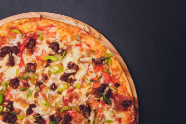 Tahtada kağıt üzerinde pizza. Siyah bir masada pizza, yakın plan. Sağlıklı sıcak yemek..