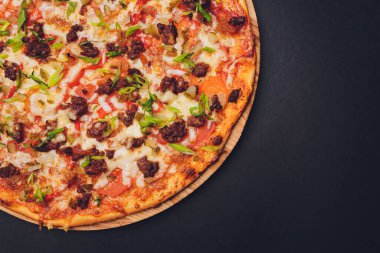 Tahtada kağıt üzerinde pizza. Siyah bir masada pizza, yakın plan. Sağlıklı sıcak yemek..
