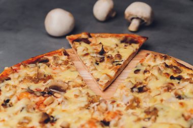 Kaba ahşap tepside ve arka planda pizza dilimleri.