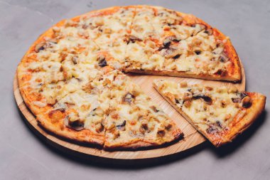 Kaba ahşap tepside ve arka planda pizza dilimleri.