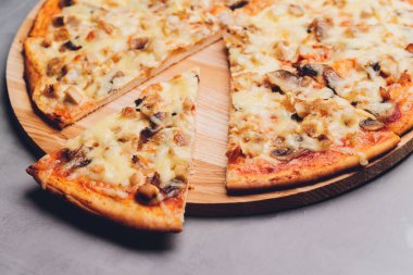 Kaba ahşap tepside ve arka planda pizza dilimleri.