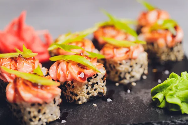 Siyah arka planda somon balıklı Maki Suşi Rolls. Zencefil ve wasabi ile. Suşi menüsü. Japon yemeği. Sushi dürümlü lezzetli Japon yemeklerini yakından çek. Yatay fotoğraf. — Stok fotoğraf
