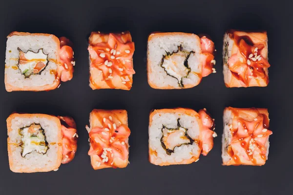 Rollos de sushi Maki con salmón sobre piedra negra sobre fondo oscuro. Con jengibre y wasabi. Menú de sushi. Comida japonesa. Primer plano de deliciosa comida japonesa con rollo de sushi. Fotografía horizontal. — Foto de Stock