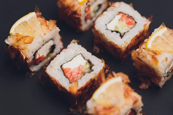 Maki Sushi Rolls lazaccal fekete kövön, sötét háttérrel. Gyömbérrel és wasabival. Sushi menü. Japán kaja. Szekrény finom japán ételeket sushi roll. Vízszintes fénykép. — Stock Fotó