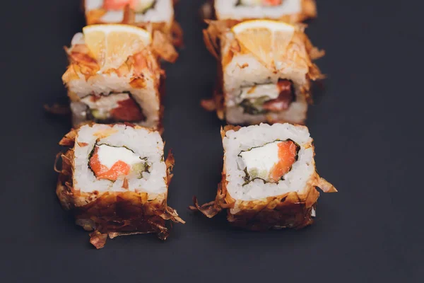 Maki Sushi Rolls lazaccal fekete kövön, sötét háttérrel. Gyömbérrel és wasabival. Sushi menü. Japán kaja. Szekrény finom japán ételeket sushi roll. Vízszintes fénykép. — Stock Fotó