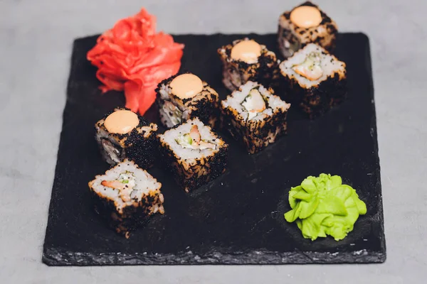 Siyah arka planda somon balıklı Maki Suşi Rolls. Zencefil ve wasabi ile. Suşi menüsü. Japon yemeği. Sushi dürümlü lezzetli Japon yemeklerini yakından çek. Yatay fotoğraf. — Stok fotoğraf