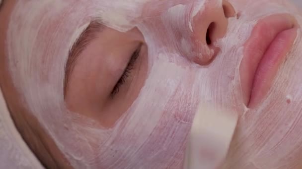 Widok z góry na piękną młodą kobietę otrzymującą leczenie skóry twarzy. Kosmetyk przeprowadza zabieg stosowania kremu. — Wideo stockowe
