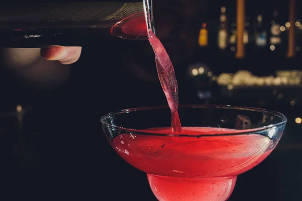 Dettagli da vicino del barman versare vodka cocktail cosmopolita in vetro martini. — Foto Stock