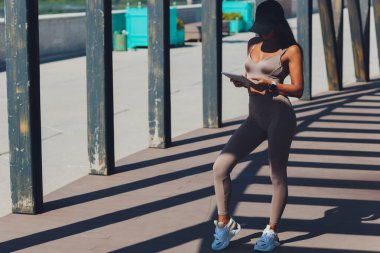 Parkta tablet tablet kullanan mutlu sarışın iş kadını portresi. Elinde dijital tablet bilgisayarla gülümseyen bir kızın ön görüntüsü. Parlak güneş ışığı.