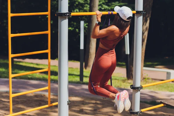 Motivierte, konzentrierte athletische Frau, die Sport treibt, trainiert, mit Gummistreifen trainiert, elastisches Seil für Muskeldehnung und Krafttraining verwendet. — Stockfoto