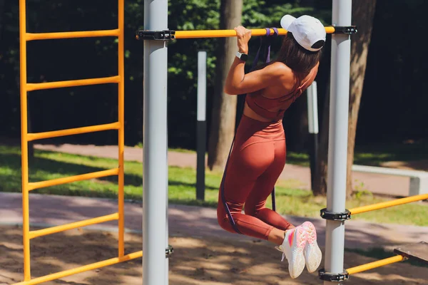 Motivated, concentrated athletic woman doing sports, training , exercising with rubber expander stripe, using elastic rope for muscle stretching and strength workouts. — Stock Photo, Image