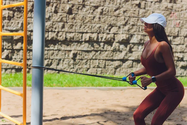 Uma jovem esportista com faixa elástica fazendo exercício ao ar livre na cidade. — Fotografia de Stock