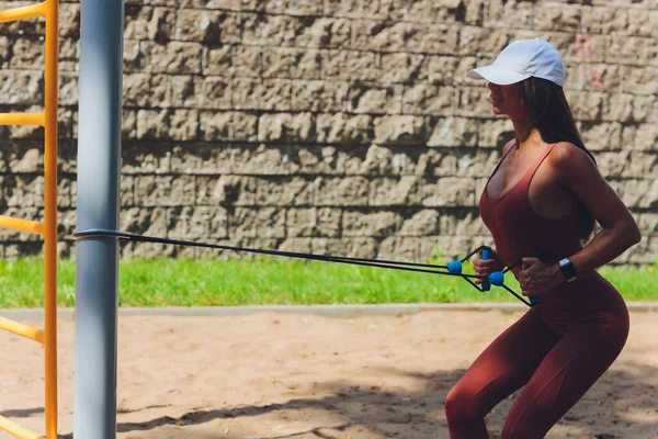 A young sportswoman with elastic band doing exercise outdoors in city. — Stock Photo, Image