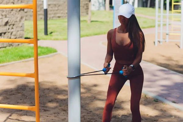 Eine junge Sportlerin mit Gummiband macht Sport im Freien in der Stadt. — Stockfoto