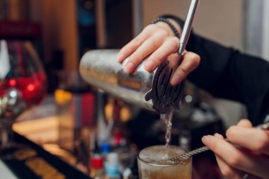 Barmen barın arka planında ince dilimler halinde taze portakal meyvesi kokteyli hazırlıyor..