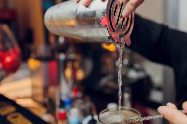 Barmen barın arka planında ince dilimler halinde taze portakal meyvesi kokteyli hazırlıyor..