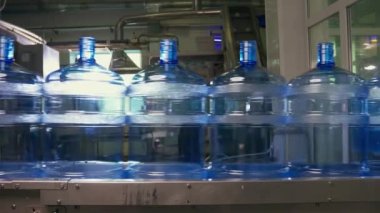 Su fabrikası - saf kaynak suyunu küçük şişelere işlemek ve şişelemek için su şişeleme hattı. Seçici odak.
