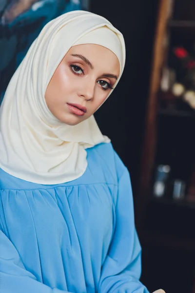 Retrato de una hermosa mujer musulmana asiática modelo con blusa blanca y hiyab azul posando sobre una cortina blanca como fondo en vista de cerca. —  Fotos de Stock