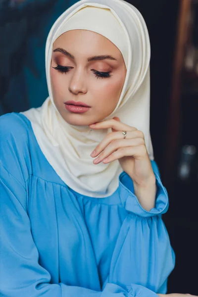 Porträt einer schönen asiatischen muslimischen Frau Modell trägt weiße Bluse und blauen Hijab posiert auf weißem Vorhang als Hintergrund in Nahaufnahme. — Stockfoto