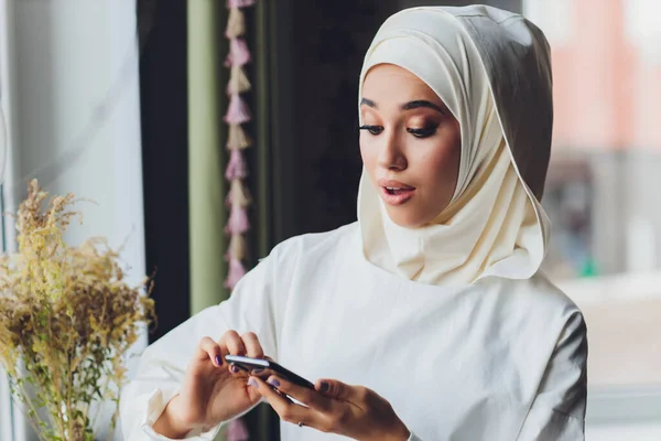 Мусульманка разговаривает по мобильному телефону в кафе. — стоковое фото