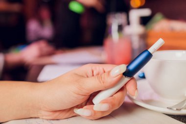 Isı yakmayan tütün ürünü teknolojisi. Sigara içmeden önce elinde e-sigara tutan kadın..