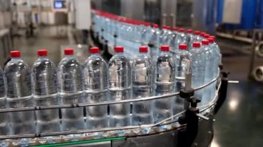 İçki fabrikasının konveyör bandındaki yeni plastik şişeler..