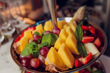 Meyve karışımı. Şeftali, üzüm, elma, karpuz, kavun, ahududu, erik. Tabaktaki meyve parçaları beyaz ahşap bir arka planda yatıyor. Boşluğu kopyala, metin için boşluk.