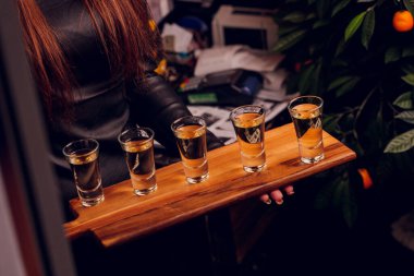 Bar tezgahında servis edilen sert alkollü içkilerin çeşitleri. Arka planda bulanık şişeler.