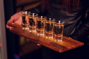 Bar tezgahında servis edilen sert alkollü içkilerin çeşitleri. Arka planda bulanık şişeler.