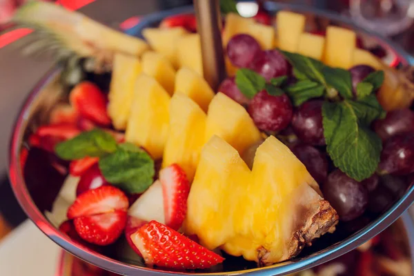 Fruitmix. Perzik, druiven, appel, watermeloen, meloen, frambozen, pruimen. Stukken fruit op een bord liggen op een witte houten ondergrond. Kopieer ruimte, ruimte voor tekst. — Stockfoto