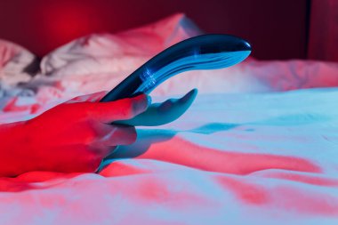 Yatak odasında elinde vibratör tutan bir kadın..