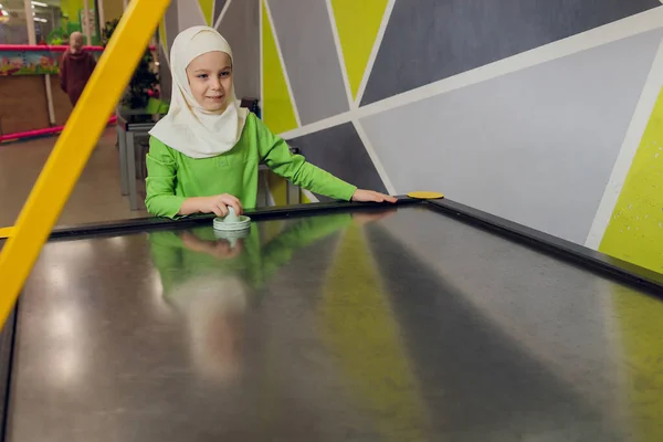 Kinder in muslimischer Kleidung spielen Airhockey. — Stockfoto