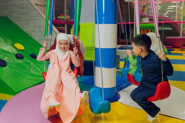 Kinder in muslimischen Kleidern fahren Schaukel. — Stockfoto