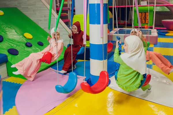 Kinder in muslimischen Kleidern fahren Schaukel. — Stockfoto