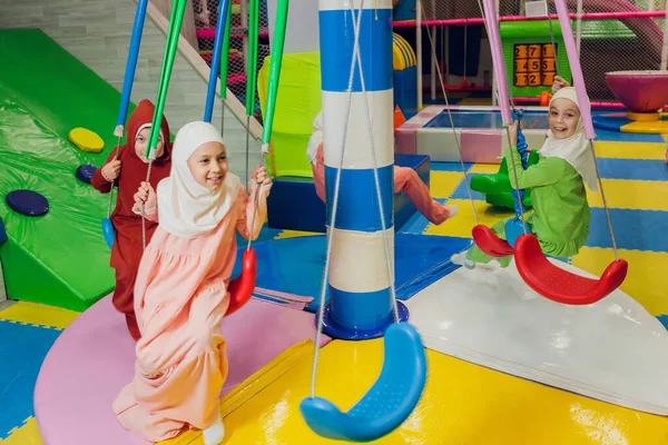 Kinder in muslimischen Kleidern fahren Schaukel. — Stockfoto