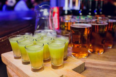 Bar tezgahında servis edilen sert alkollü içkilerin çeşitleri. Arka planda bulanık şişeler.