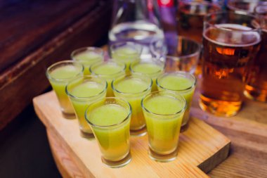 Bar tezgahında servis edilen sert alkollü içkilerin çeşitleri. Arka planda bulanık şişeler.