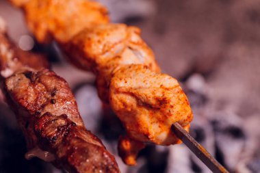 Metal şişte pişen ızgara kebap. Barbeküde pişmiş et. Barbekü taze et dilimleri. Geleneksel doğu yemeği, şiş kebap. Kömür ve alevler üzerine ızgara, piknik, sokak yemekleri.