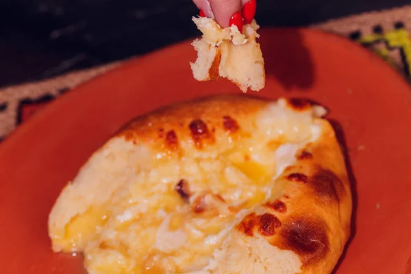 Mulher está comendo adjarian khachapuri com as mãos, esmagando gema de ovo. — Fotografia de Stock