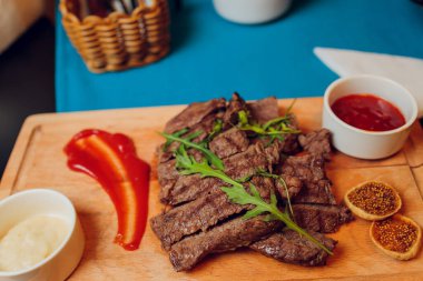 Koyu ahşap arka planda ızgara biftek ve biber sosu..