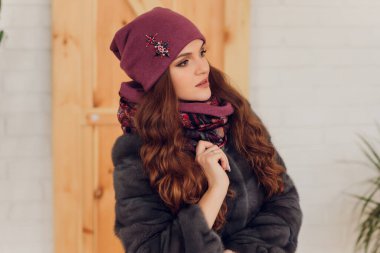 Heyecandan yana bakan mutlu, güzel bir kadın. Örgü, kalın şapka ve eldiven giyen bir kız..