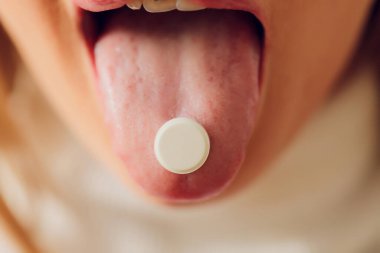 Hap alıyorum. Kadın hap alıyor. Diline yakın çekim..