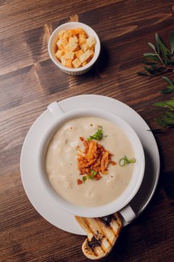 Beyaz tencerelerde mantar çorbası, peçete, ahşap zemin.