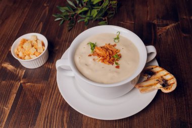 Beyaz tencerelerde mantar çorbası, peçete, ahşap zemin.