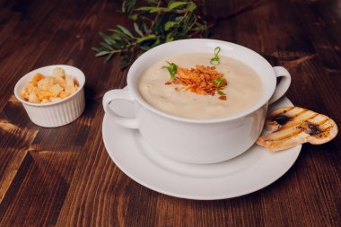 Beyaz tencerelerde mantar çorbası, peçete, ahşap zemin.