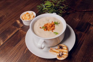 Beyaz tencerelerde mantar çorbası, peçete, ahşap zemin.