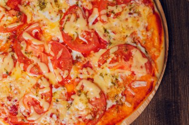 Tahta bir tabakta pizza sosisi, salam ve peynir dilimlerine ayrılmış..