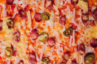 Tahta bir tabakta pizza sosisi, salam ve peynir dilimlerine ayrılmış..