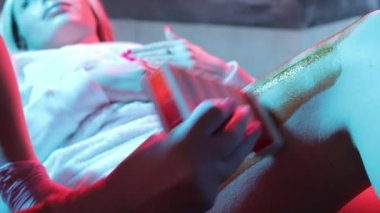 Spa 'daki genç kadın kıllarını aldırmak için bacaklarını cilalıyor..